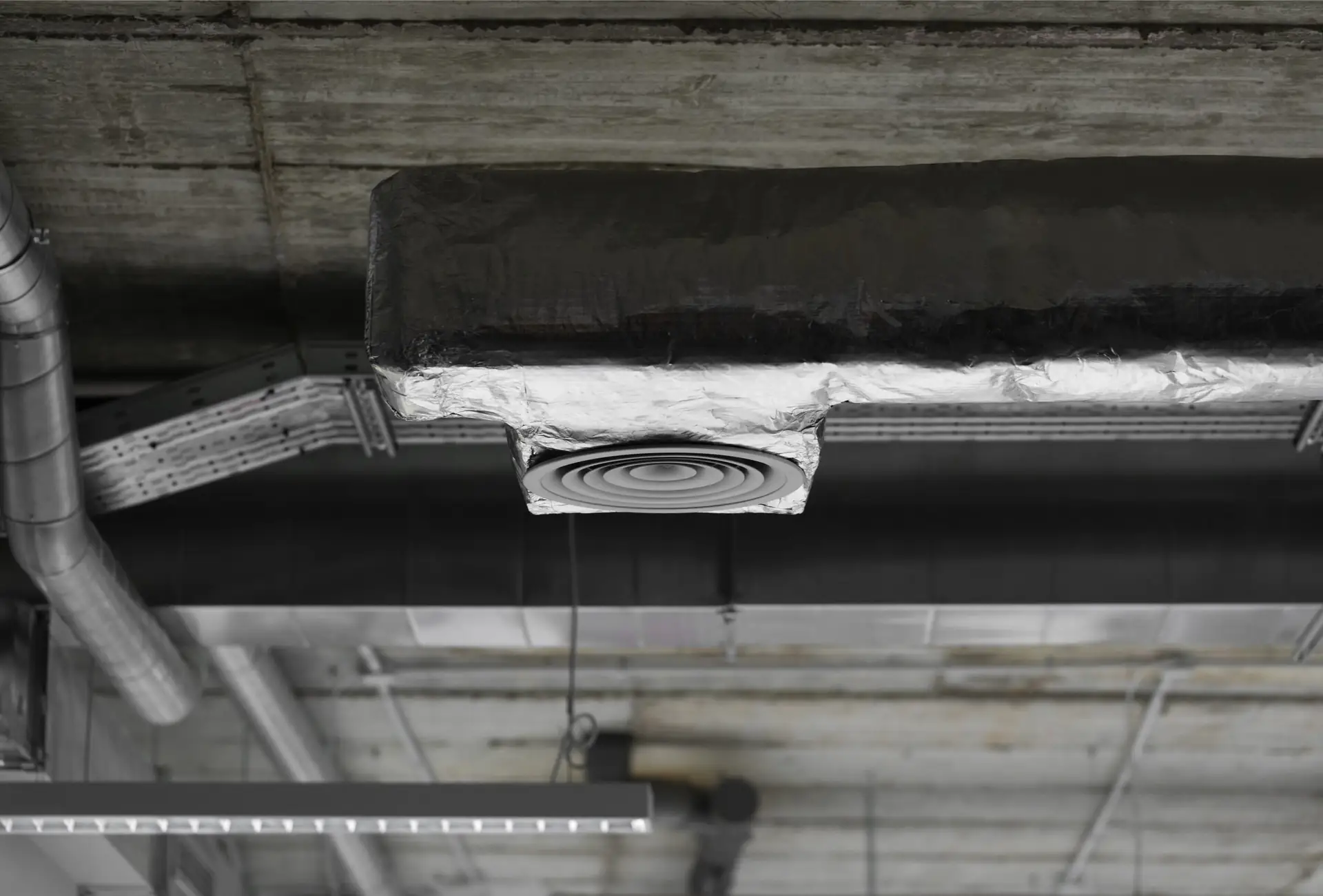 Ventilatiekanaal met rooster onder een betonnen plafond